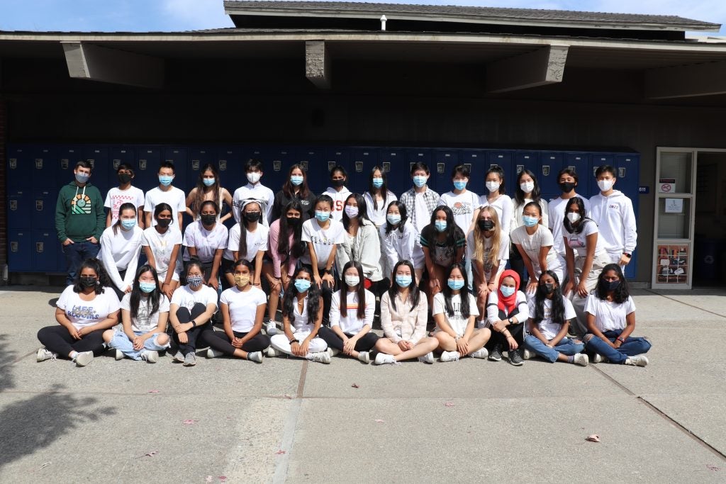 A group of students wearing masks at school all wearing white shirts