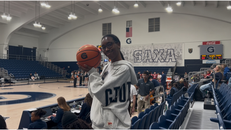 Young Black woman with glasses with a basketball in a gym