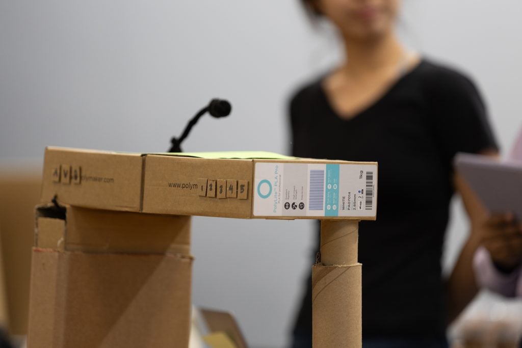 A cardboard prototype of an accessible podium with a microphone