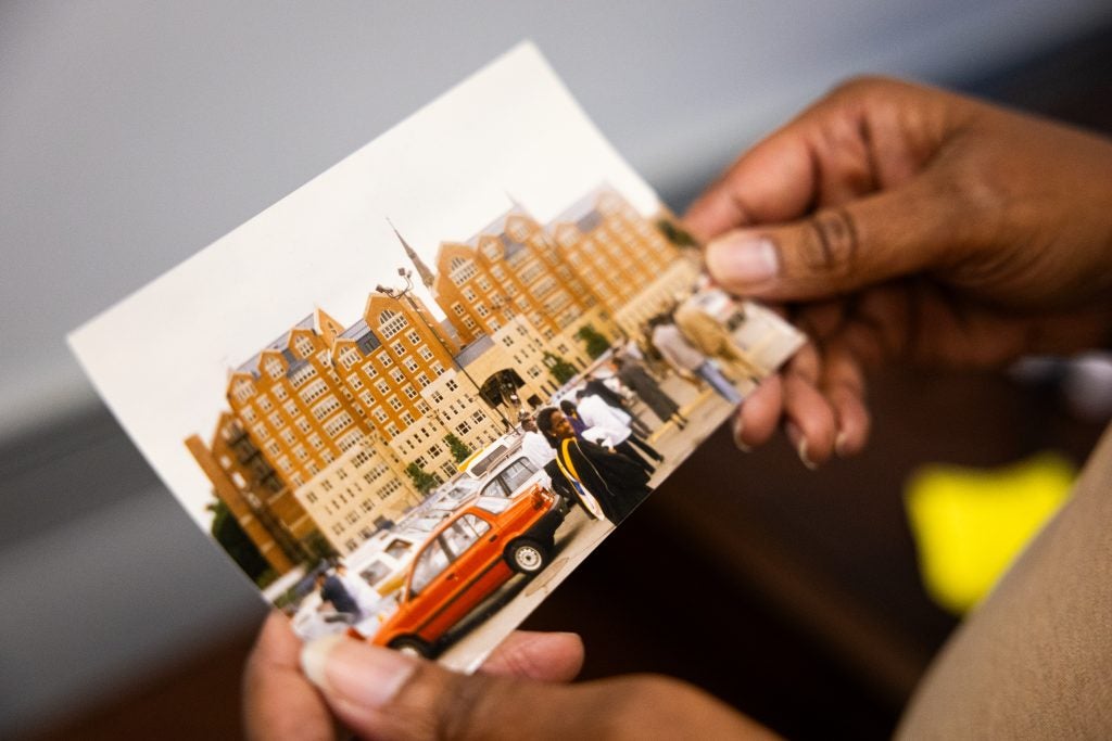 A woman holds a photo of herself on her graduation from Georgetown in 1990