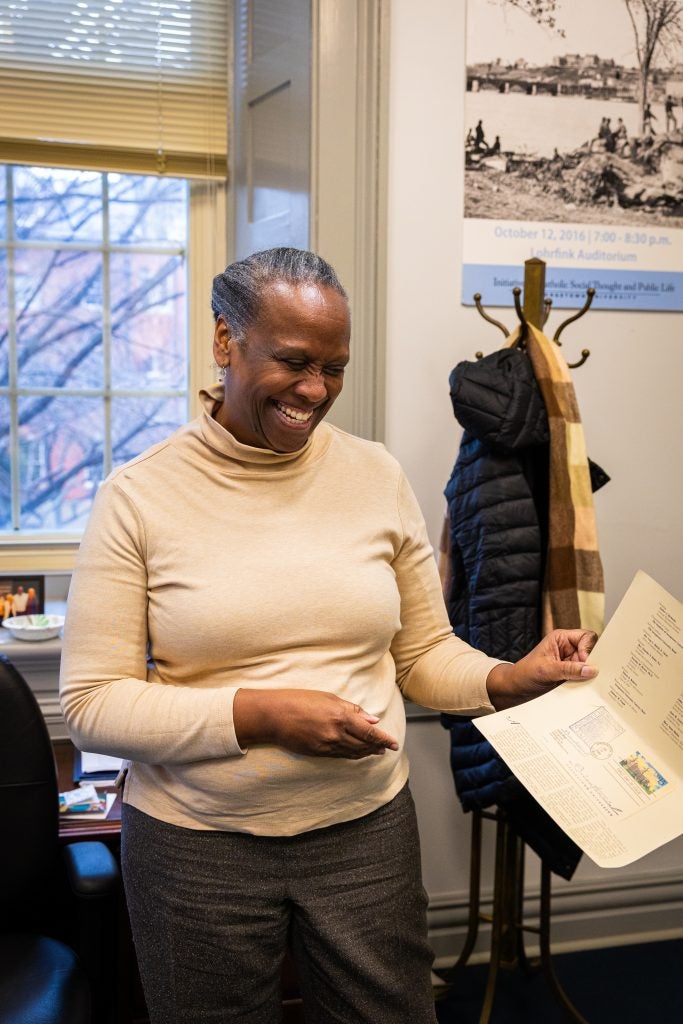 A woman smiles while holding up a piece of paper in her office