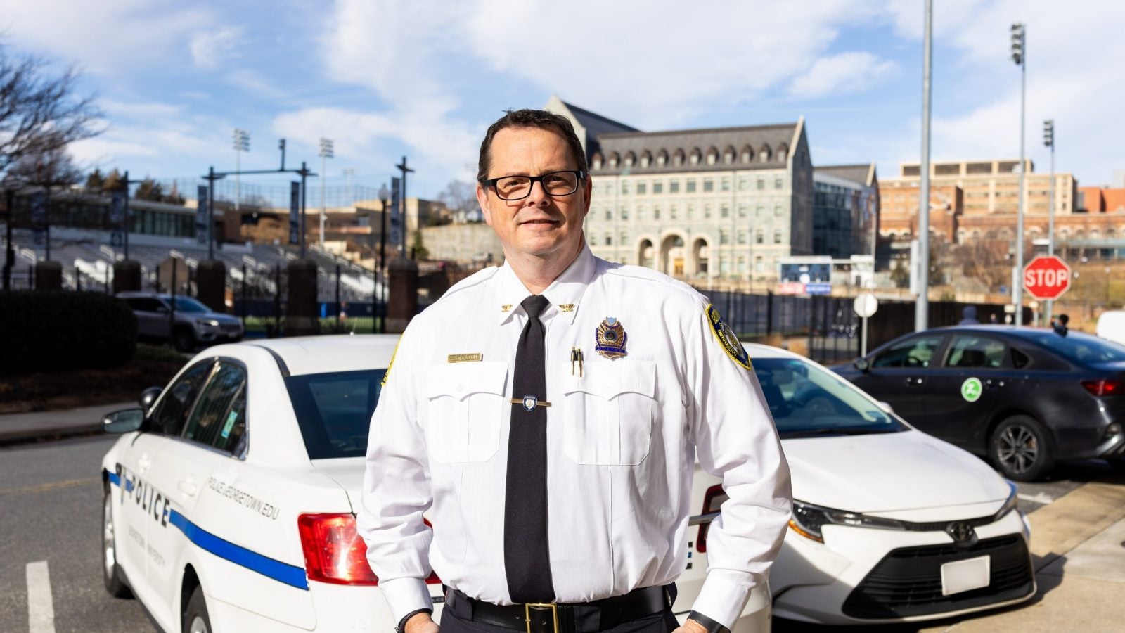 A man in a police chief uniform stands in front of a police car