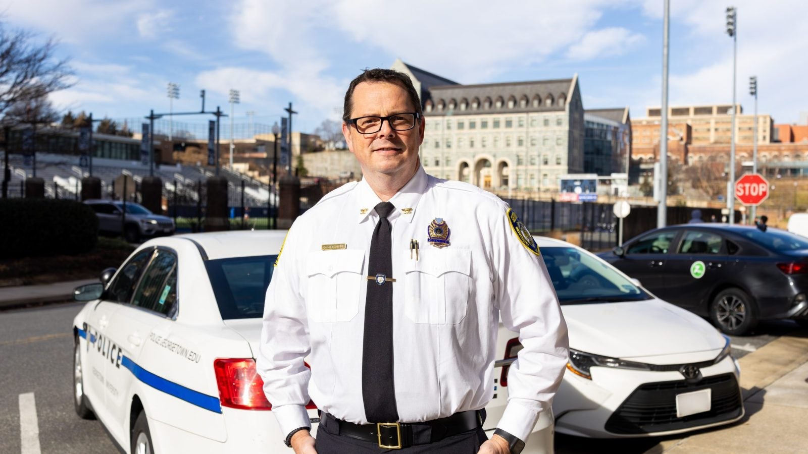 A man in a police chief uniform stands in front of a police car