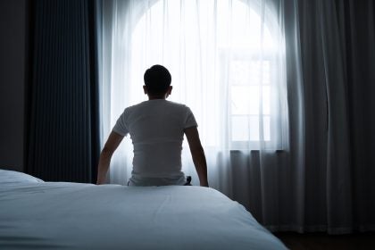 Rear view of a man sitting on bed