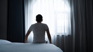 Rear view of a man sitting on bed