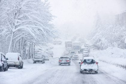 Cars drive on a snowy road during a blizzard