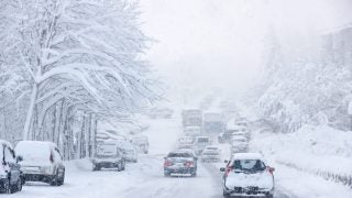 Cars drive on a snowy road during a blizzard