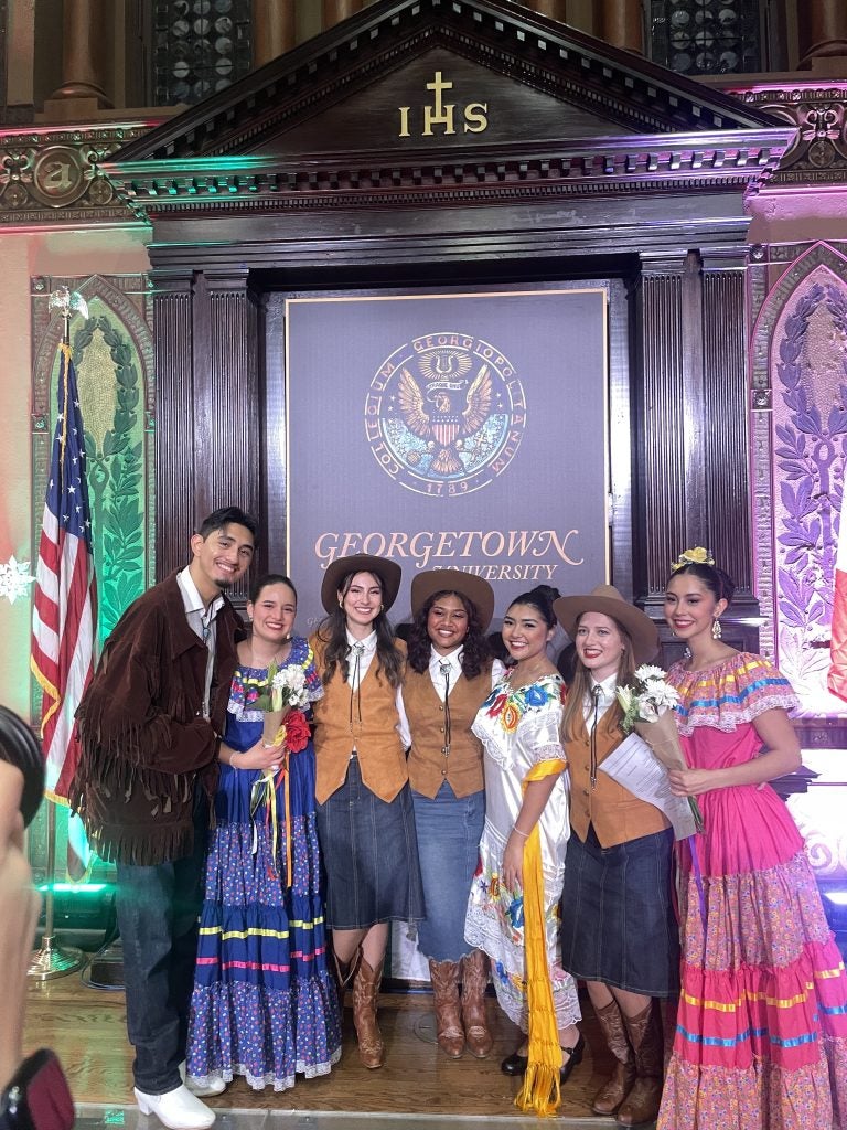 Group of students in various traditional attire smiling