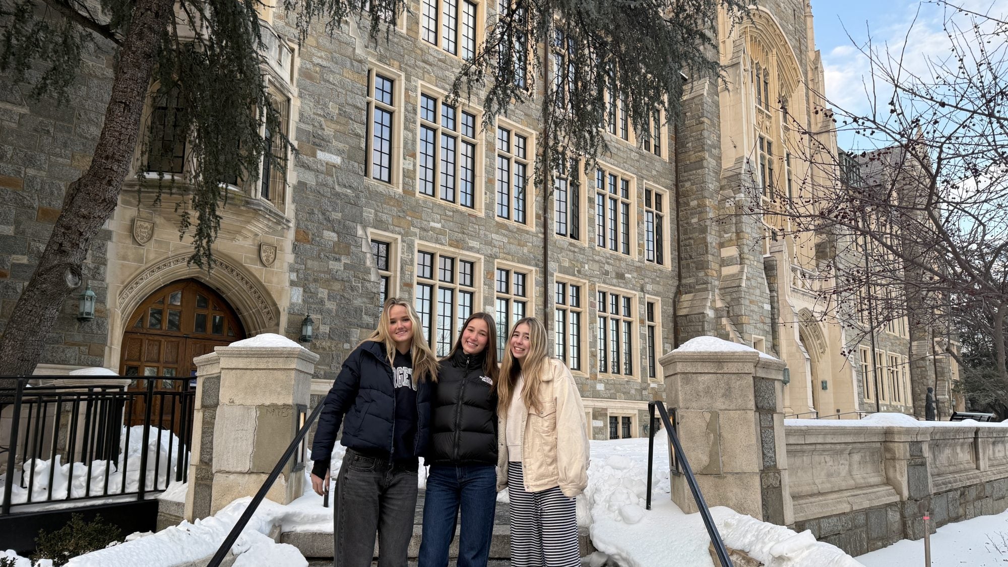 Three young students in front a university building in the snow
