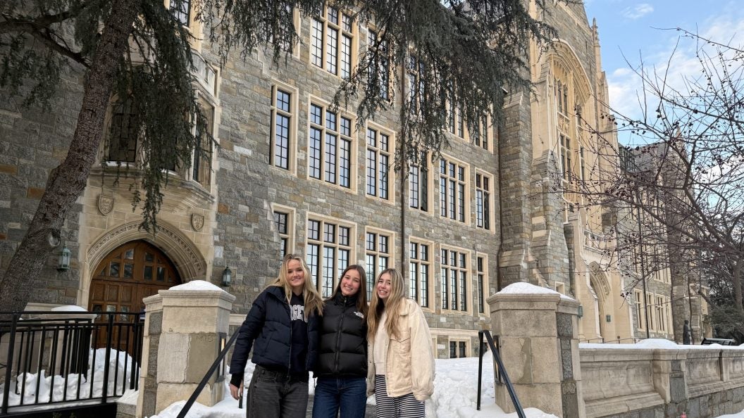 Three young students in front a university building in the snow