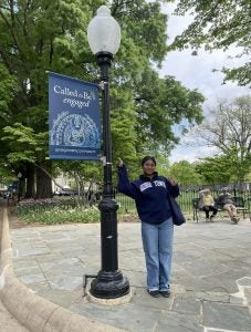 Young woman points to a lamppost with a GU sweatshirt