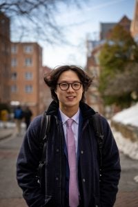 Young Asian man with glasses smiling while in a suite and tie