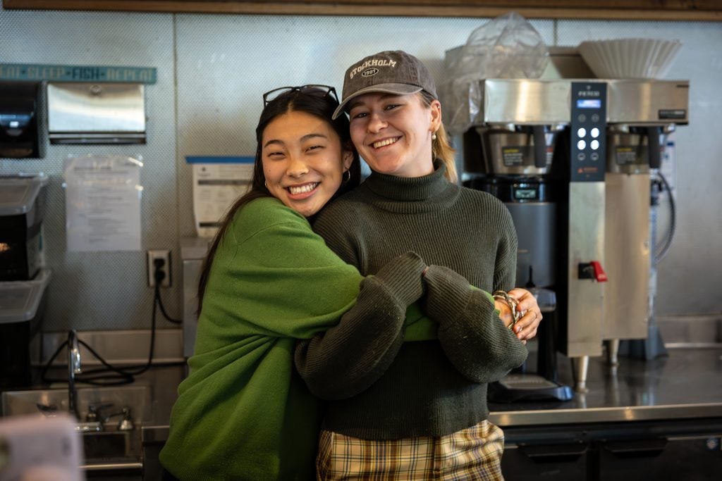 Two young women hugging each other in a coffee shop