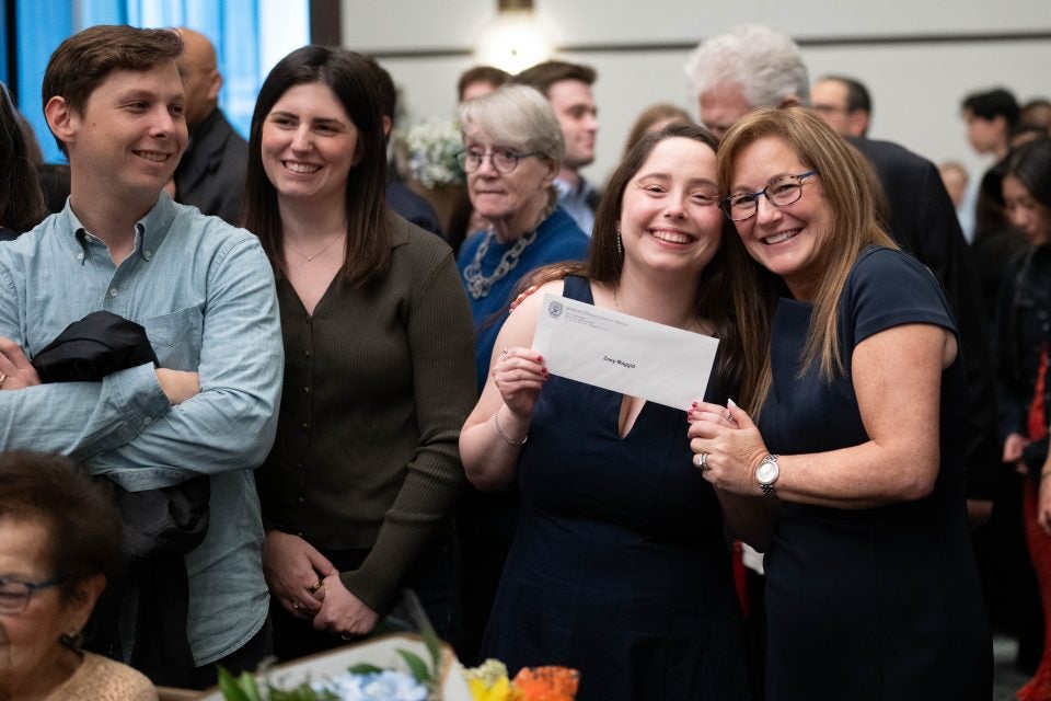 A medical student poses with a woman holding up an envelope and smiles