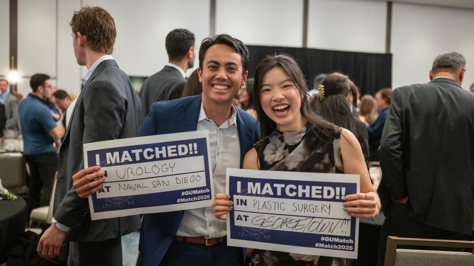 Two students smile and hold up signs of where they matched for their medical residency