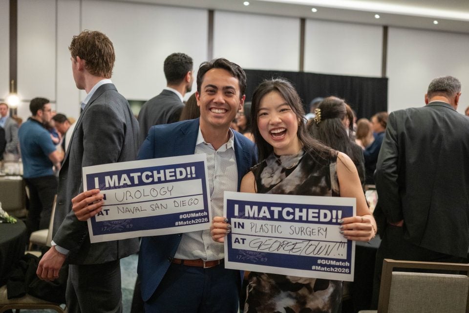 Two students smile and hold up signs of where they matched for their medical residency