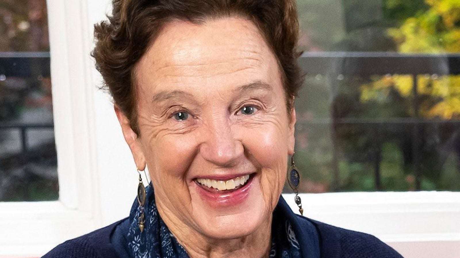 A woman in a black sweater and blue and black scarf smiles