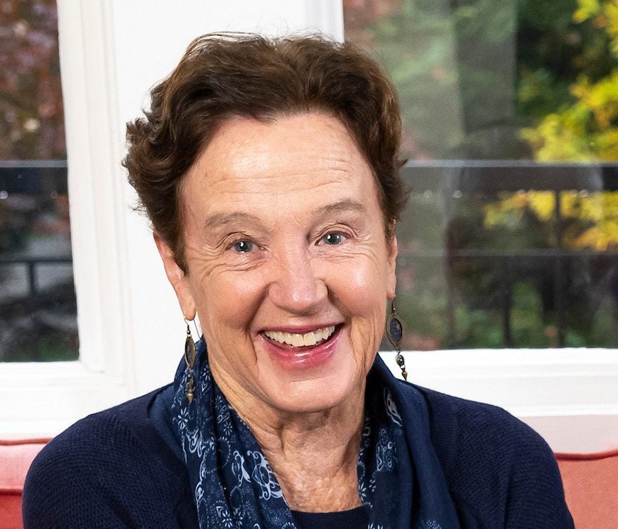 A woman in a black sweater and blue and black scarf smiles