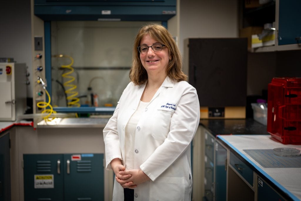 Caucasian woman with glasses wearing a white coat in a lab setting