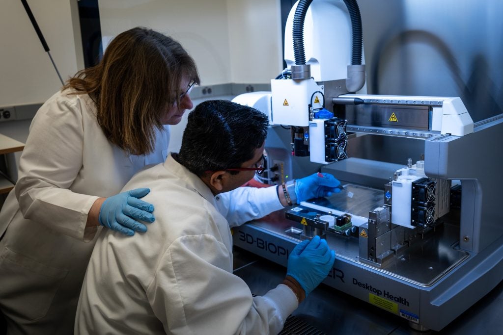Two scientists working with a 3d printer in a lab
