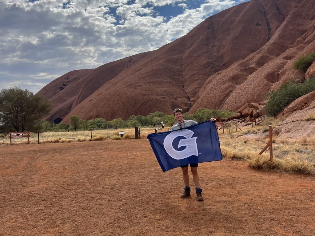 Young Caucasian man holding a GU flag at a national park
