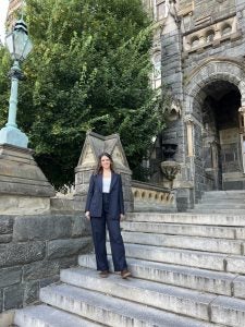 A student in a suit poses on stone steps at Georgetown