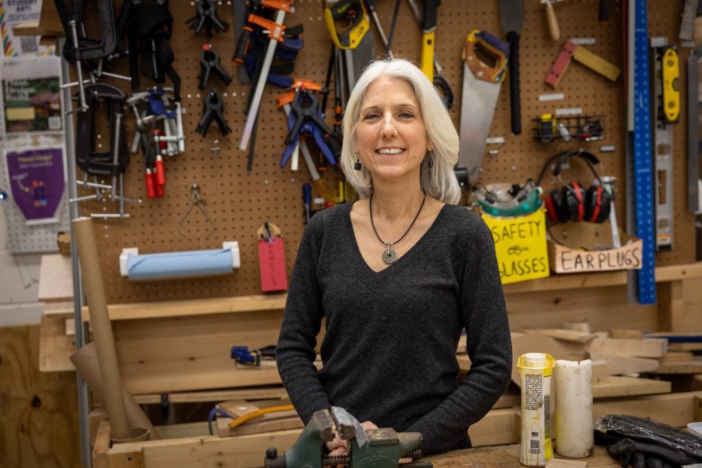 A woman stands in front of a wall of tools