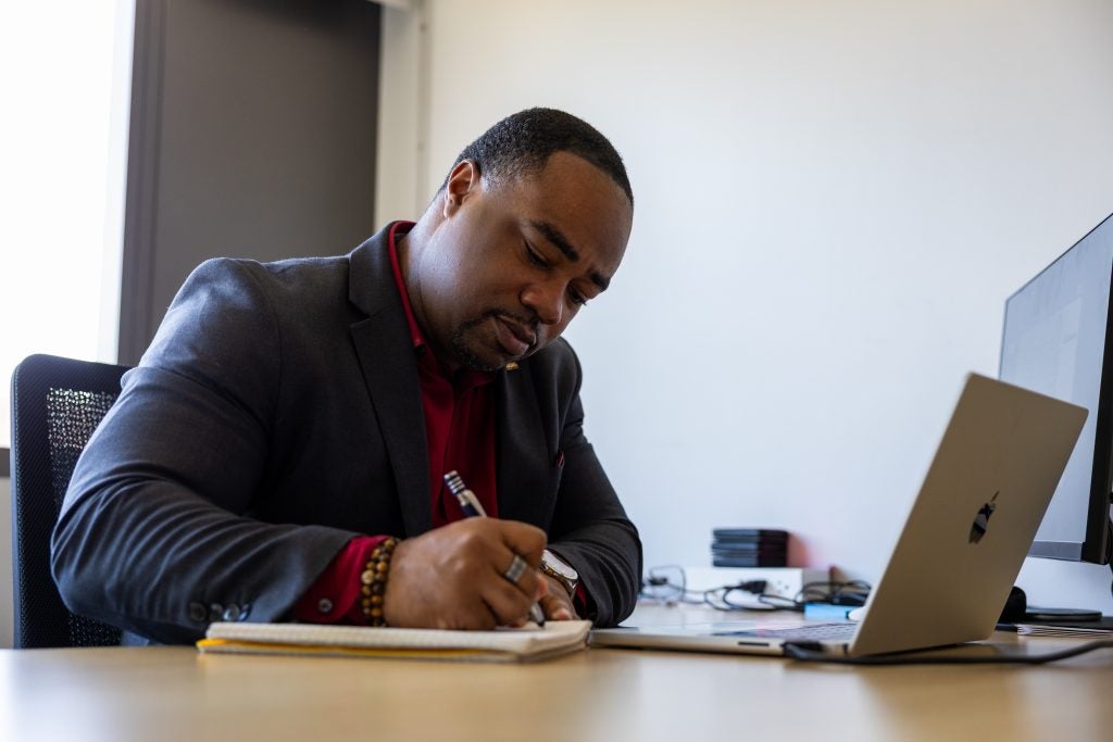 Black man in suit writes at a desk