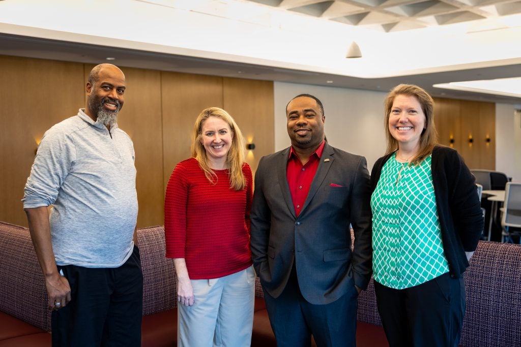 Four adults smiling for a photo