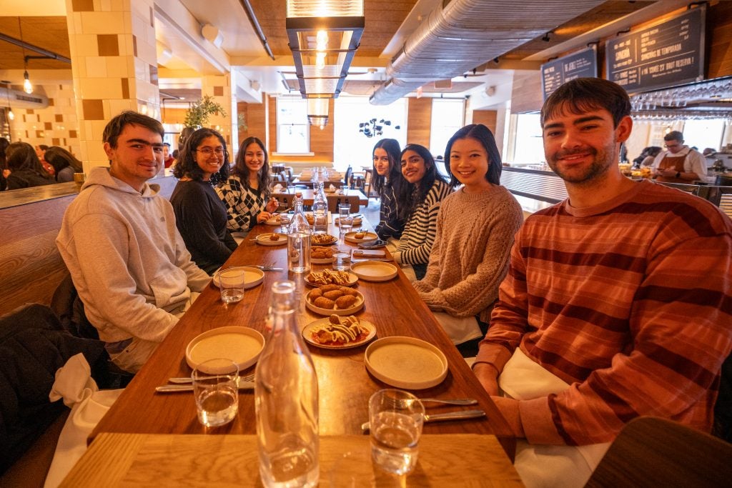 A group of young adults sit down for a meal at a restaurant
