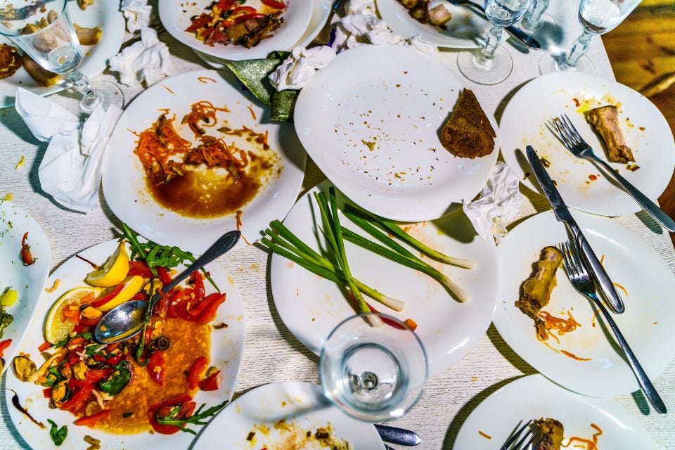 A table of white plates with uneaten food on them