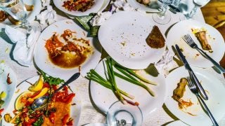 A table of white plates with uneaten food on them
