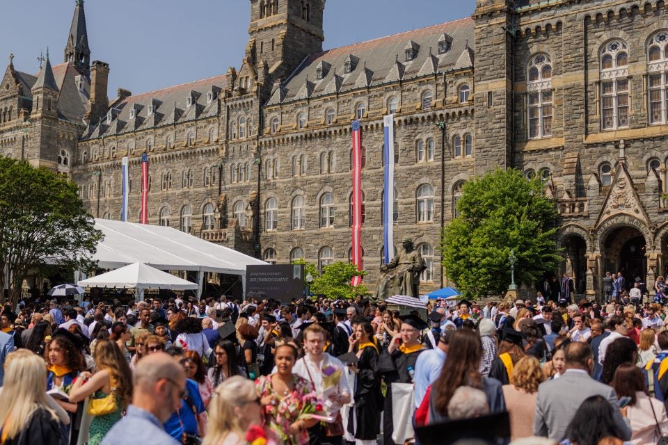 A crowd gathers in front of Healy Hall during commencement