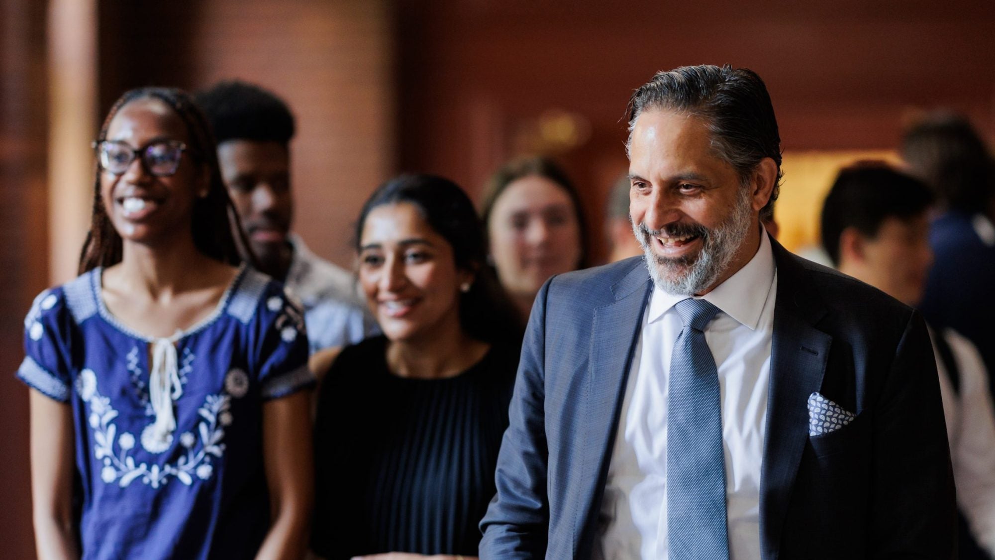 President-elect Eduardo Peñalver smiles while talking to a group of students in a hallway
