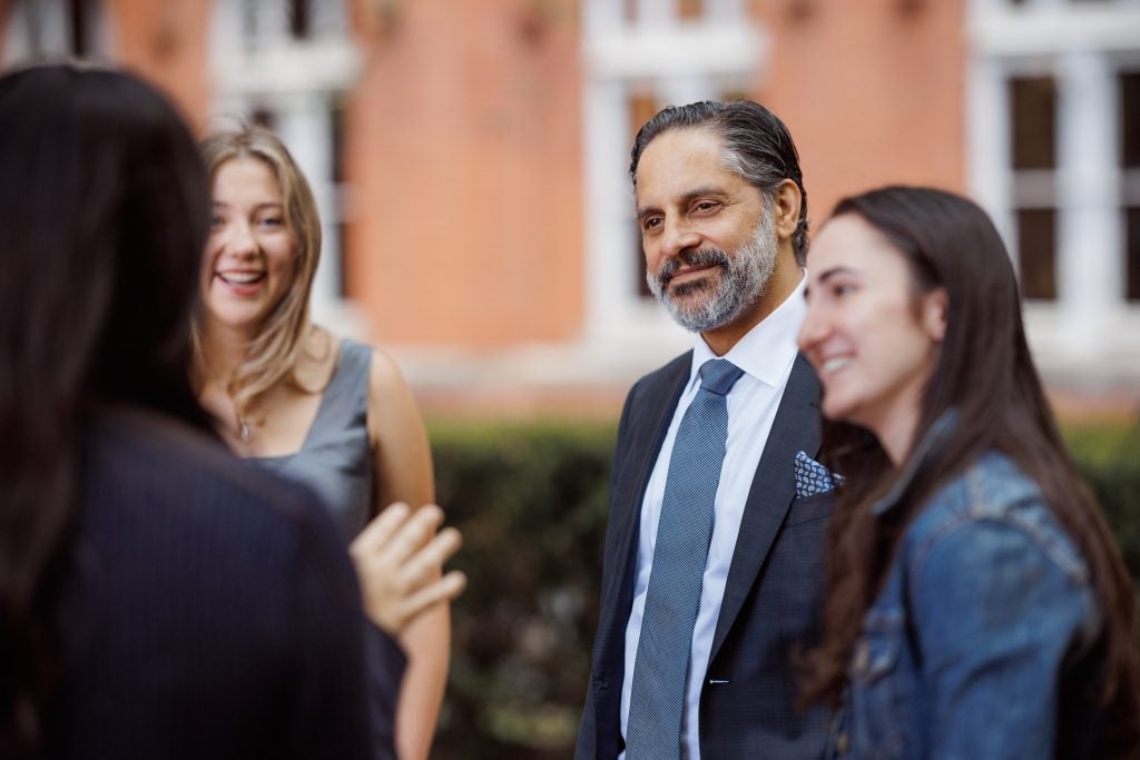 President-elect Eduardo Peñalver listens to a group of students while standing in a courtyard