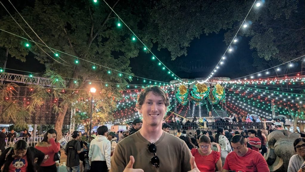 Young man gives thumbs up at a nighttime celebration