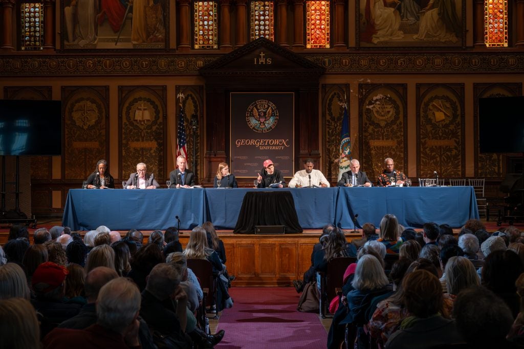 A panel of speakers during performance in Gaston Hall