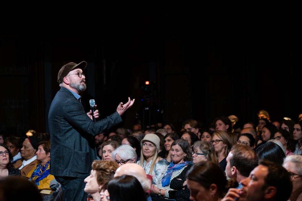 A man speaks with a mic in his hand amid an audience