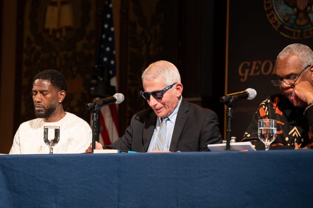Dr. Fauci in sunglasses acts his part on stage