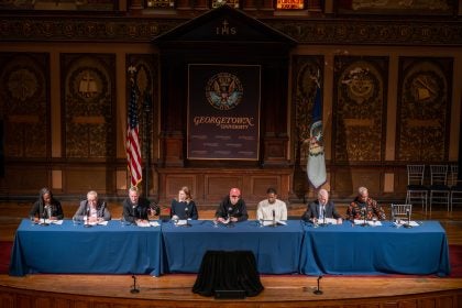 A panel on stage in Gaston Hall during performance
