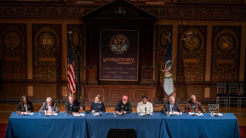A panel on stage in Gaston Hall during performance