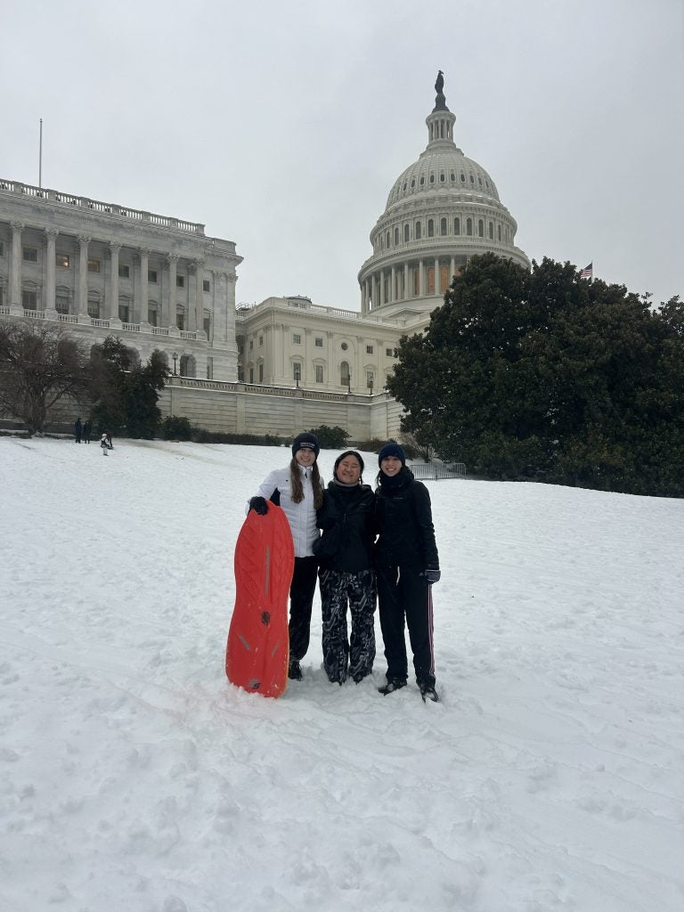 Three young women with a slide on Capitol Hill on a snow day