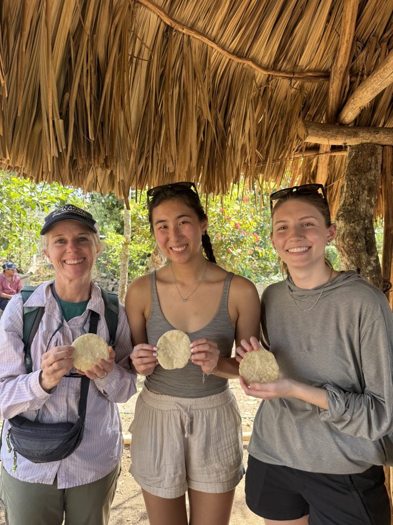 Three women hold up tortillas