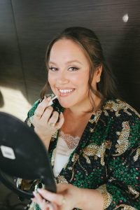 A woman applies lipstick on her wedding day