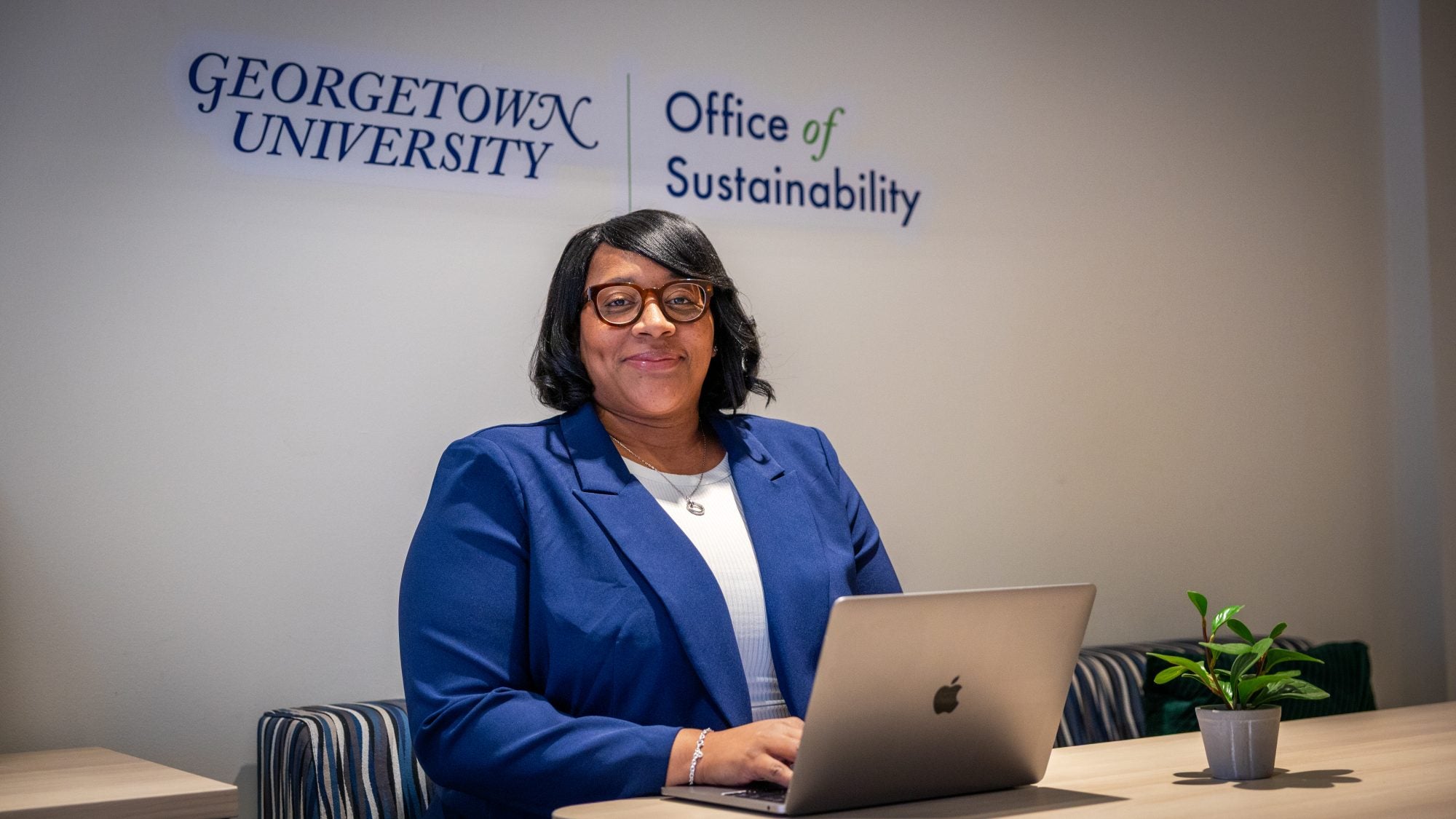 Black woman in blue suit smiling while at her desk