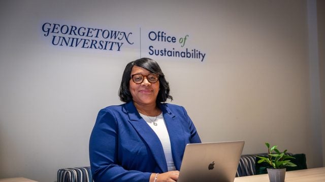 Black woman in blue suit smiling while at her desk