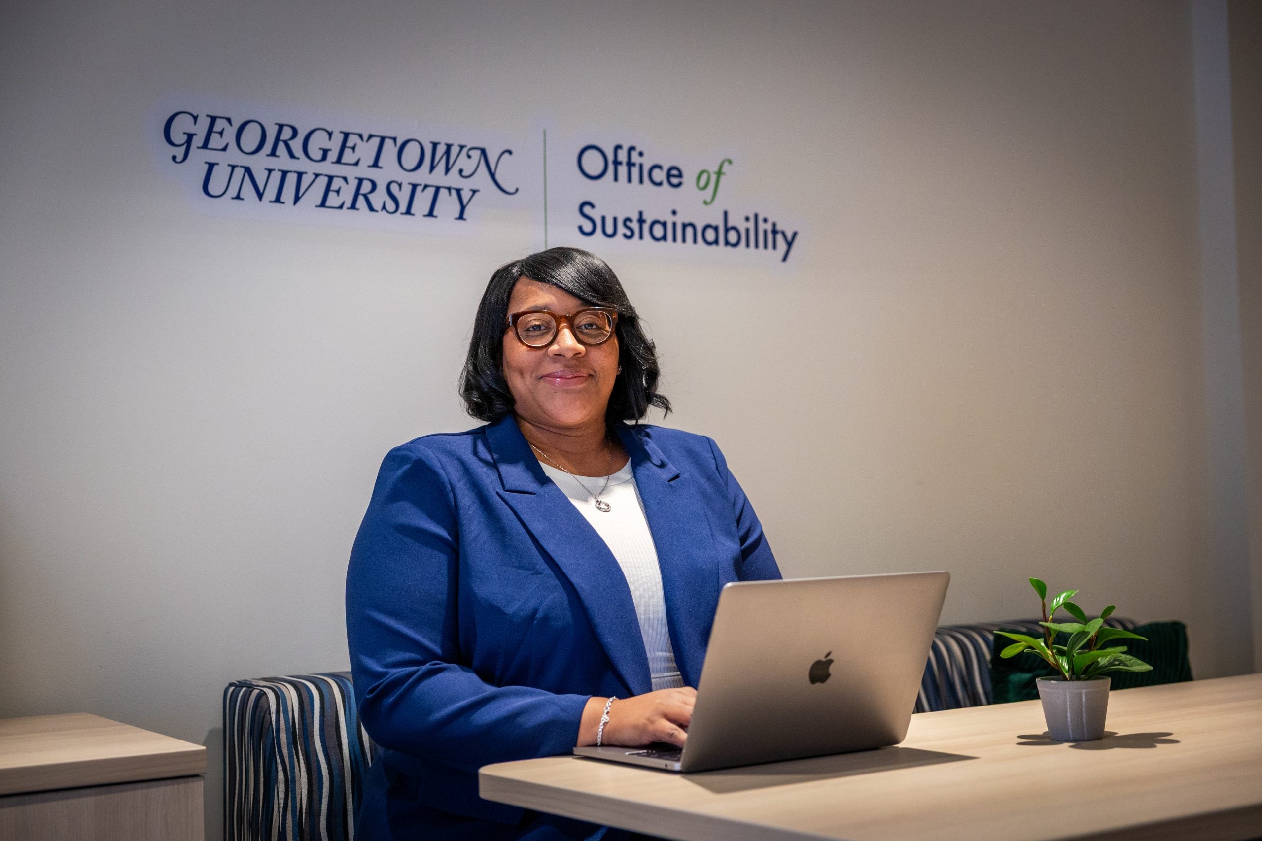 Black woman in blue suit smiling while at her desk