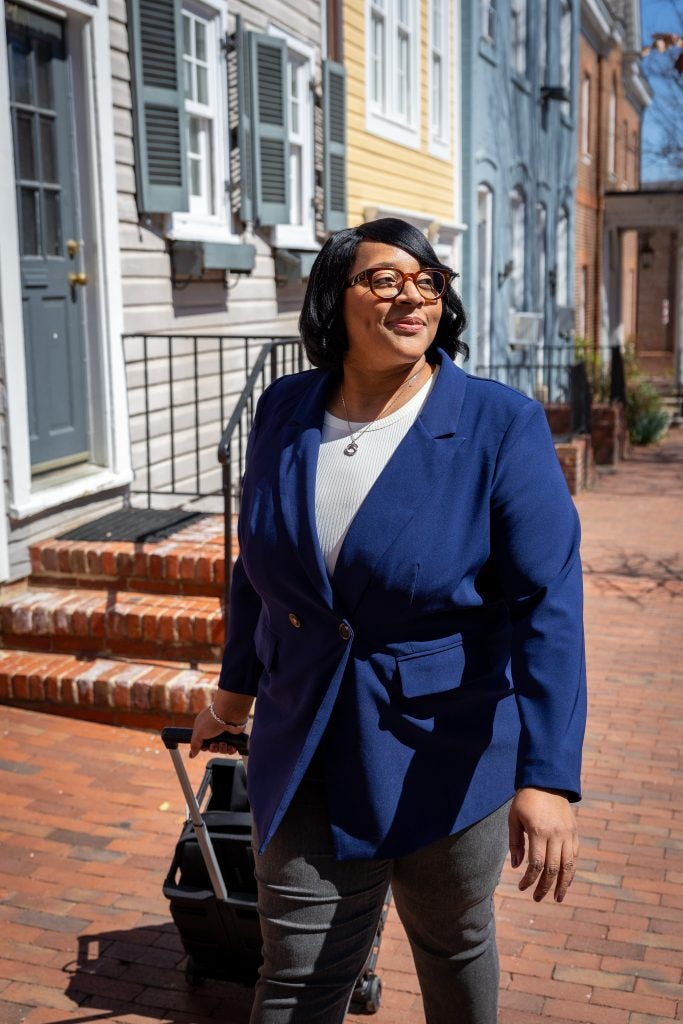 Smiling Black woman in a blue suit pulling a cart
