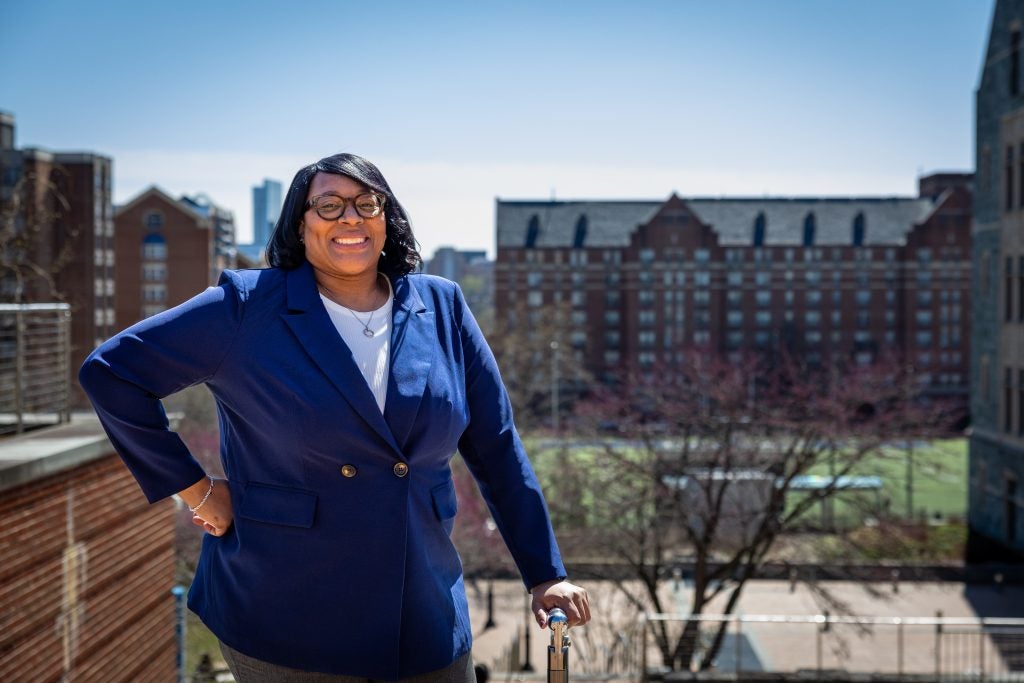 Smiling Black woman in a blue suit with campus background