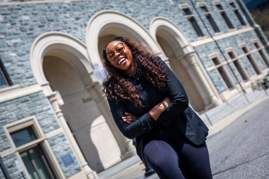 A woman laughs while walking in front of an academic building